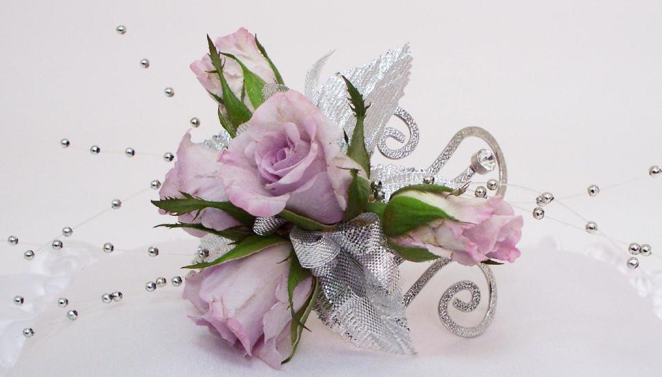 This product image released by Gillespie Florists, Inc. shows a decorative armband. The armband is created with rhinestones, five lavender sweetheart roses, silver leaves, silver bead sprays and metallic silver ribbon. (AP Photo/Gillespie Florists, Inc.)