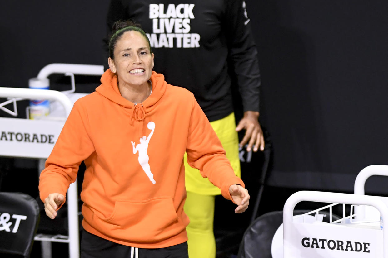 Sue Bird in the famous orange WNBA logo hoodie on the sidelines. 