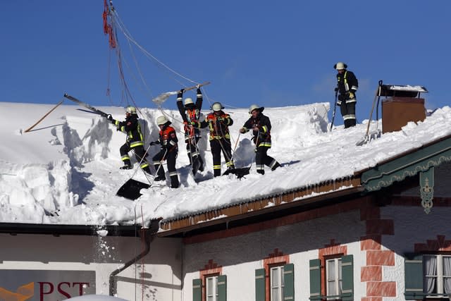 Firefighters clear snow from a roof in Inzell, Germany