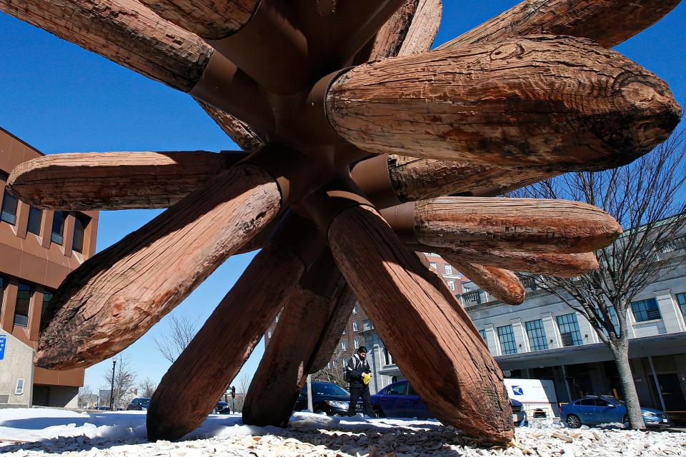 A man walks past the iconic sea urchin sculpture in front of the Federal building in downtown New Bedford.