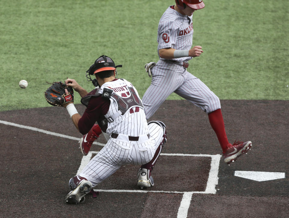 Oklahoma's John Spikerman, right, scores past Virginia Tech's Cade Hunter, left, in the first inning of an NCAA college baseball super regional game in Blacksburg, Va., Friday, June 10, 2022. (AP Photo/Matt Gentry)