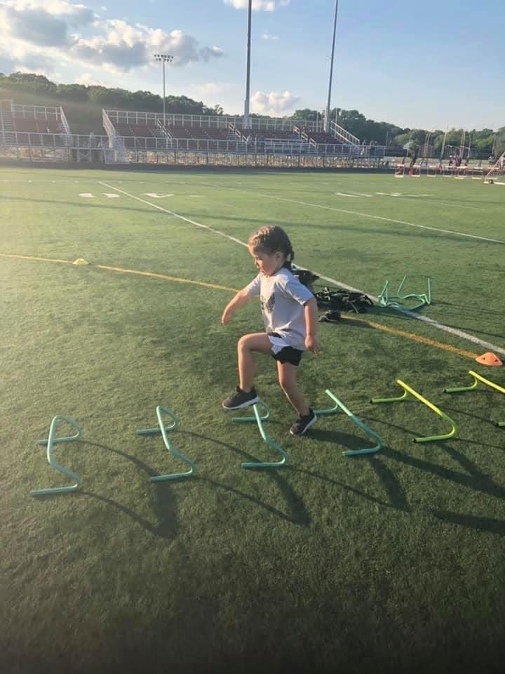 A young girl performs track and field stunts on the football field at B.M.C Durfee High school.