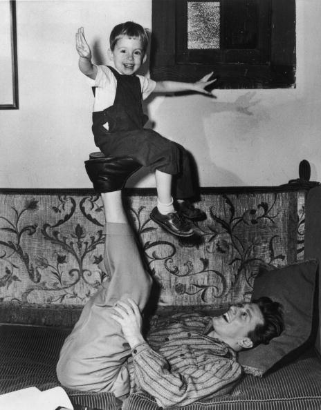 <p>Kirk plays with his son Michael by balancing him on the soles of his feet. </p>