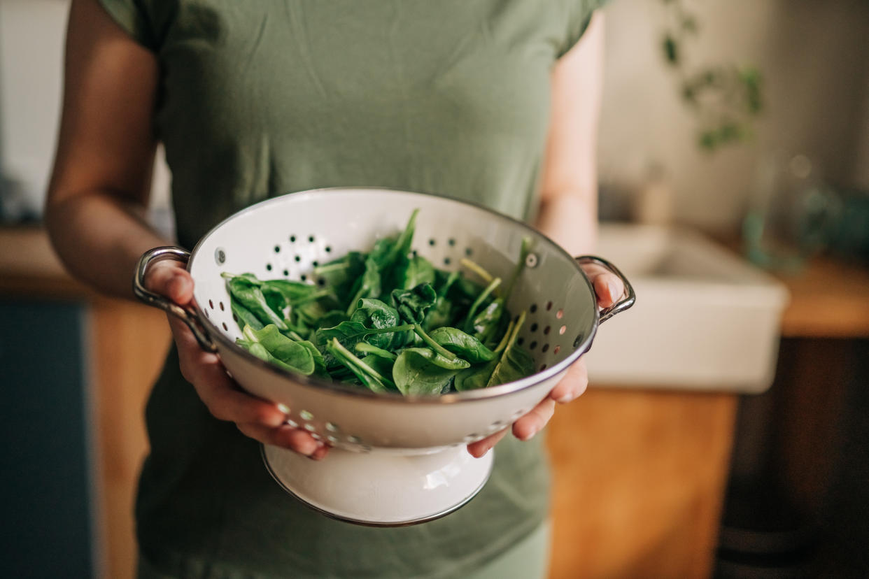 Woman with a bowl of leafy greens, which can increase iron levels. (Getty Images)