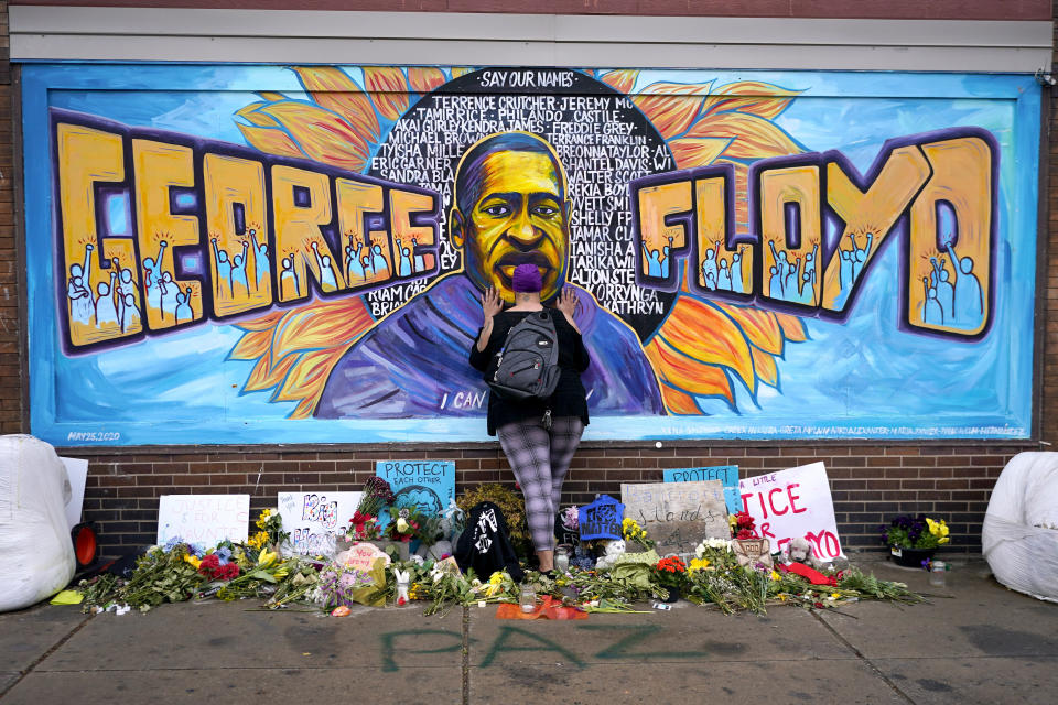 FILE - In this Friday, April 23, 2021 file photo, Damarra Atkins pays respect to George Floyd at a mural at George Floyd Square in Minneapolis. Newly released video that shows Minneapolis police officers talking about “hunting people” during unrest following the death of George Floyd is now becoming an issue in the upcoming citywide election as Mayor Jacob Frey seeks a second term and residents will vote on whether they want to replace the police department with a new agency. (AP Photo/Julio Cortez, File)