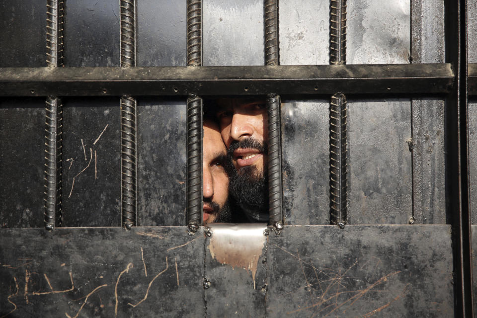 Taliban prisoners watch through the door inside the prison after an attack in the city of Jalalabad, east of Kabul, Afghanistan, Monday, Aug. 3, 2020. An Islamic State group attack on the prison in eastern Afghanistan holding hundreds of its members raged on Monday after killing people in fighting overnight, a local official said. (AP Photo/Rahmat Gul)