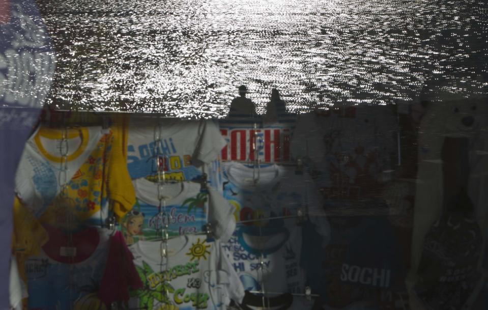 A couple sitting on the beach are reflected in a shop window in Sochi