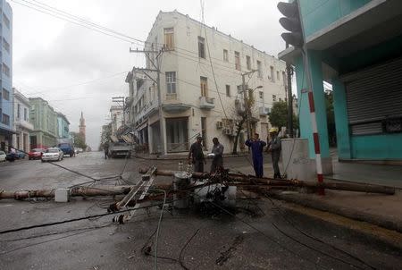 Workers stand near an electricity pole that was knocked down by heavy winds, ahead of the passing of Hurricane Irma, in Havana, Cuba September 9, 2017. REUTERS/Stringer