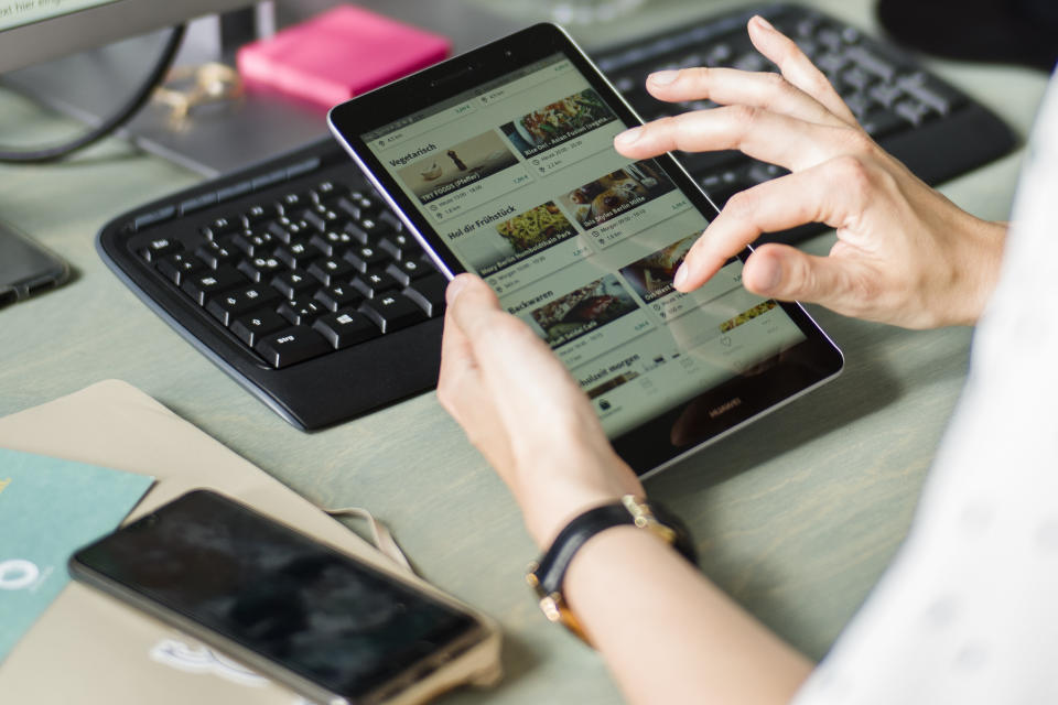 In this Tuesday, May 21, 2019 photo, Franziska Lienert spokeswoman of the company which runs the food sharing app 'Too Good To Go', uses a tablet to find a restaurant participating with the food sharing community, during an interview with the Associated Press in Berlin. In Germany, growing numbers of people use modern technology such as phone apps to help reduce food waste. In an effort to cut down on climate-wrecking carbon dioxide emissions created by food waste, they build online communities to share food before throwing it away. (AP Photo/Markus Schreiber)