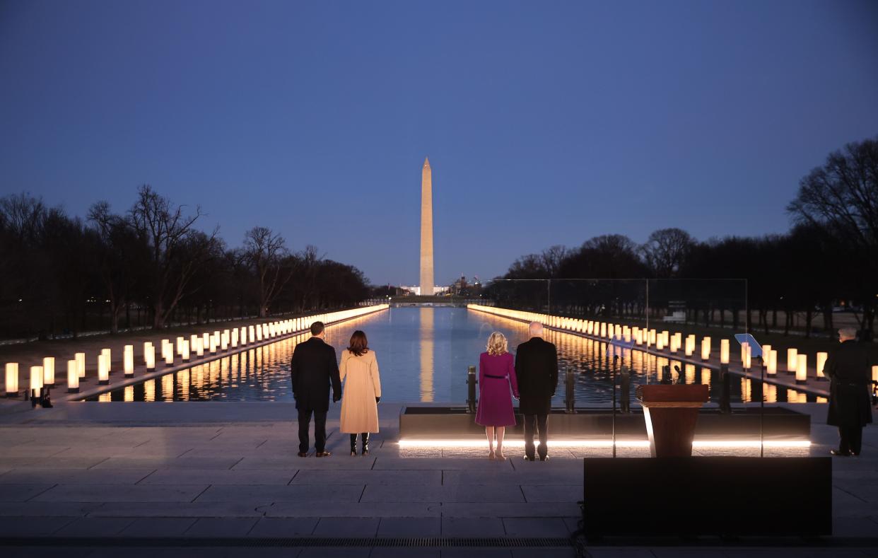 (L-R) Douglas Emhoff, U.S. Vice President-elect Kamala Harris, Dr. Jill Biden and U.S. President-elect Joe Biden look down the National Mall as lamps are lit to honor the nearly 400,000 American victims of the coronavirus pandemic at the Lincoln Memorial Reflecting Pool on Jan. 19, 2021, in Washington, DC.