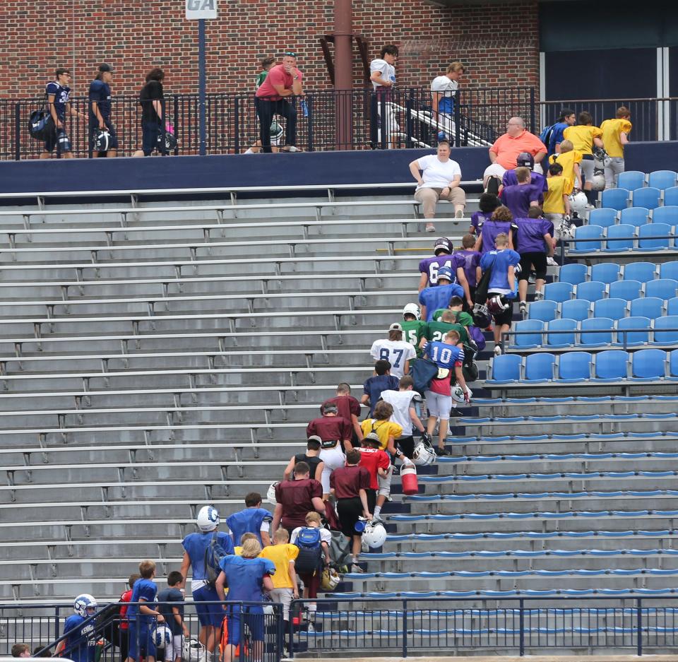 As lightning was spotted in the sky before the rain fell, campers walk up the stairs at Wildcat Stadium during Tuesday's session at the annual UNH Youth Football Camp.