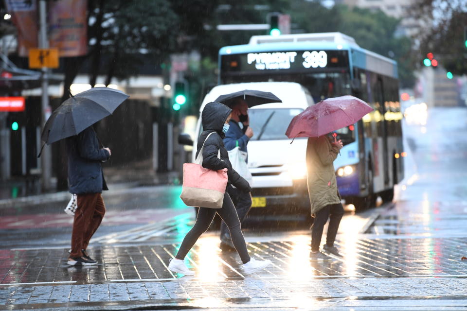 SYDNEY, AUSTRALIA - JULY 10: People wearing face masks and holding umbrellas in the Town Hall area of the CBD on a Saturday afternoon on July 10, 2021 in Sydney, Australia. Lockdown restrictions are in place across Greater Sydney, the Blue Mountains, the Central Coast and Wollongong as NSW health authorities work to contain the growing COVID-19 cluster. Restrictions will remain in place until midnight on Friday 16 July. All residents in areas subject to stay-at-home orders are only permitted to leave their homes for essential reasons, including purchasing essential goods, accessing or providing care or healthcare, work, education and exercise. (Photo by James D. Morgan/Getty Images)