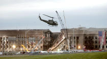 ARLINGTON, VA - SEPTEMBER 14, 2001: A military helicopter flies in front of the Pentagon at the impact site where a hijacked airliner crashed into the building September 14, 2001 in Arlington, Virginia. This September 11 marks ten years since members of Al Qaeda hijacked four planes, attacking the World Trade Center and the Pentagon and crashing one in Shanksville, Pennsylvania, killing nearly 3,000 people in all. The effects continue to resonate across the global political landscape, as the United States concluded a nearly decade-long search for Al Qaeda leader Osama bin Laden, killing him in May 2011, and struggles to wind down two wars in Afghanistan and Iraq. (Photo by Stephen J. Boitano/Getty Images)