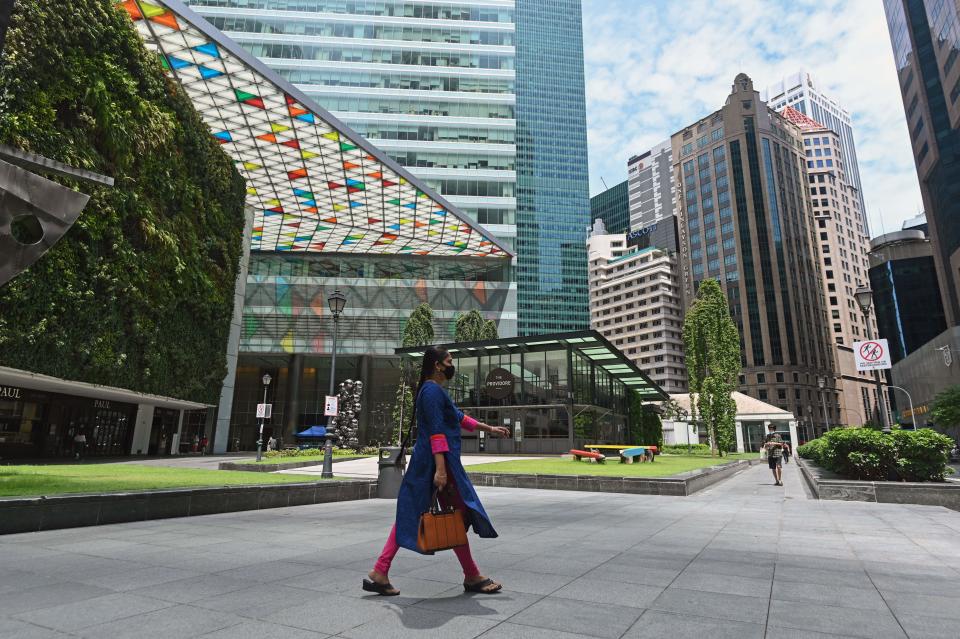 A woman wearing a facemask as preventive measure against the spread of the COVID-19 coronavirus walks at the Raffles Place central business district in Singapore on May 22, 2020. (Photo by ROSLAN RAHMAN / AFP) (Photo by ROSLAN RAHMAN/AFP via Getty Images)