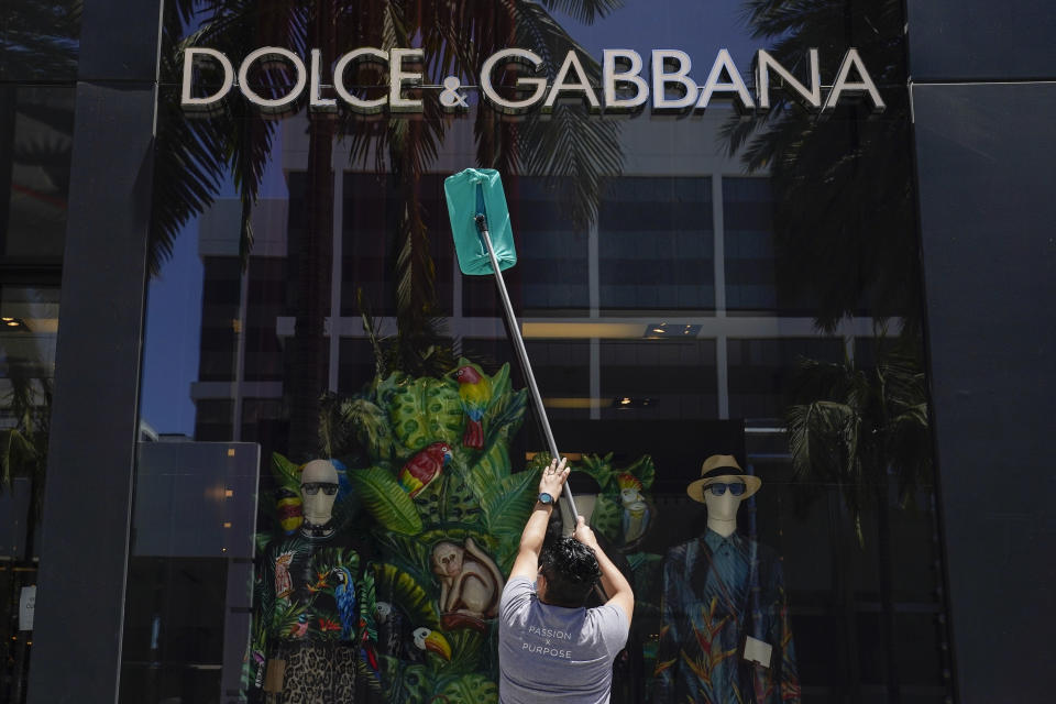 Dulce Gonzalez cleans the front window of Dolce & Gabbana on Rodeo Drive Tuesday, May 19, 2020, in Beverly Hills, Calif. (AP Photo/Ashley Landis)