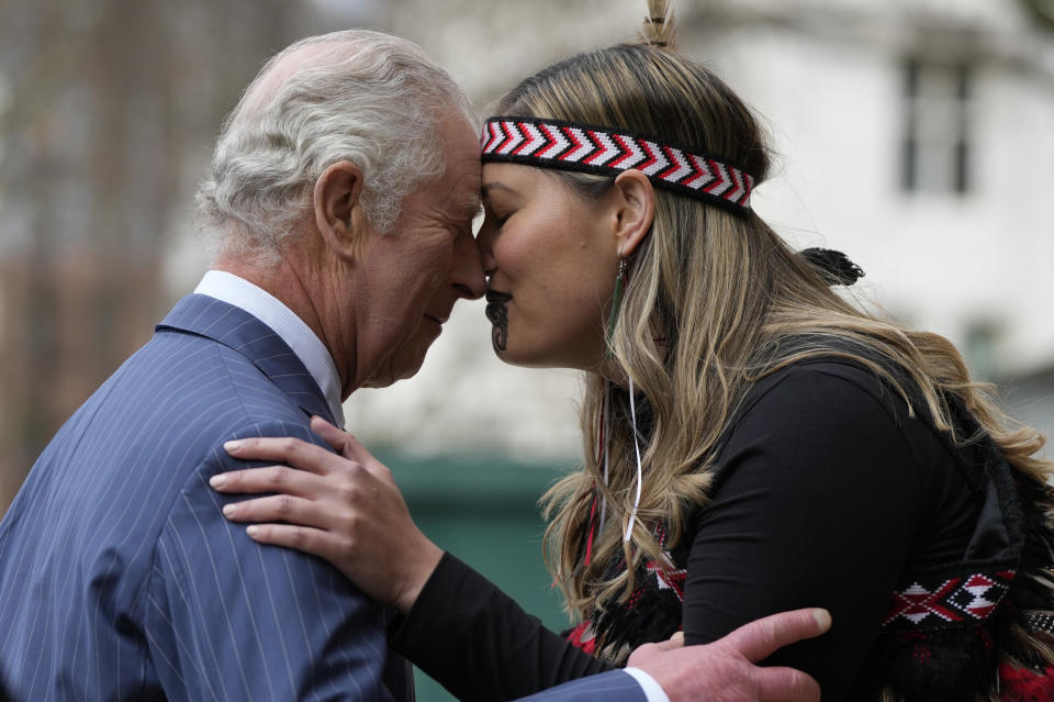 FILE Britain's King Charles III is greeted by a member of a Maori group as he arrives to attend the annual Commonwealth Day service at Westminster Abbey in London, Monday, March 13, 2023. A year after the death of Queen Elizabeth II triggered questions about the future of the British monarchy, King Charles III’s reign has been marked more by continuity than transformation, by changes in style rather than substance. (AP Photo/Frank Augstein, File)