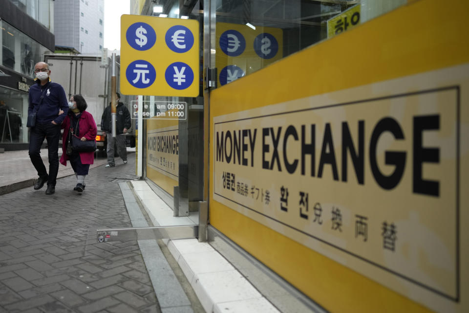 People walk near a sign of foreign currency outside a money exchange office at a shopping district in Seoul, South Korea, Tuesday, April 11, 2023. Stocks were mostly higher in Asia on Tuesday after a mixed session on Wall Street dominated by speculation the Federal Reserve may tap the brakes again on financial markets and the economy by raising interest rates. (AP Photo/Lee Jin-man)