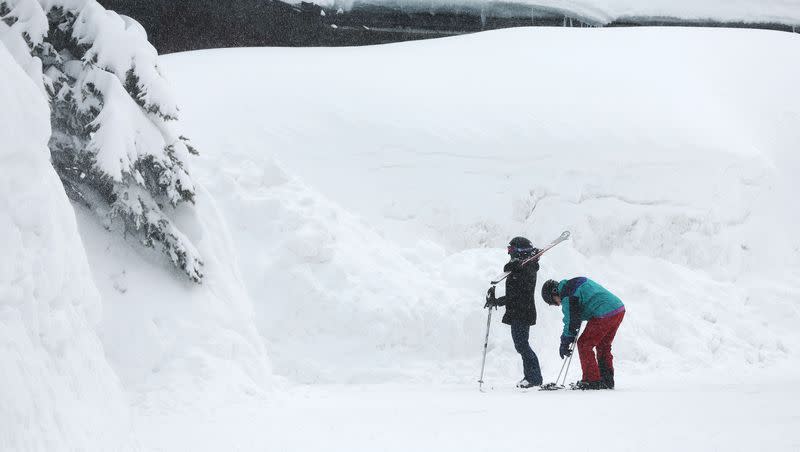 Skiers walk below towering snowbanks at Solitude in Big Cottonwood Canyon on Tuesday, April 4, 2023. The record snowpack became one of the top news stories in Utah in 2023.