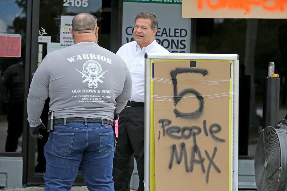 Gun shop owner Charlie Berrane talks to his employee outside Warriors Gun Range and Gun Shop in Doral, March 24, 2020. The shop is experiencing soaring sales of guns and ammo as people worry about the repercussions of the coronavirus pandemic.