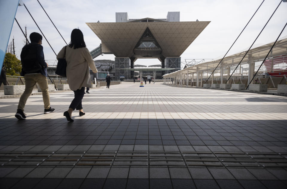 People walk towards the Tokyo International Exhibition Center, also known as Tokyo Big Sight, in Tokyo Thursday, April 8, 2021. The exhibition center is a planned venue for the Tokyo 2020 Olympic and Paralympic Games, rescheduled to start in July 2021. Many preparations are still up in the air as organizers try to figure out how to hold the postponed games in the middle of a pandemic. (AP Photo/Hiro Komae)