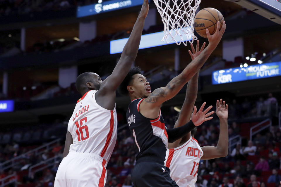 Portland Trail Blazers guard Anfernee Simons (1) lays up a shot between Houston Rockets forwards Usman Garuba (16) and Tari Eason (17) during the first half of an NBA basketball game Saturday, Dec. 17, 2022, in Houston. (AP Photo/Michael Wyke)