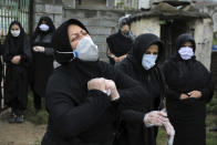 FILE - In this April 30, 2020, file photo, relatives of a victim who died from the coronavirus, mourn at the gate of a cemetery, in the outskirts of the city of Babol, in north of Iran. As coronavirus infections reached new heights in Iran, overwhelming its hospitals and driving up its death toll, the country’s health minister gave a rare speech criticizing his own government’s refusal to enforce basic health measures. (AP Photo/Ebrahim Noroozi, File)