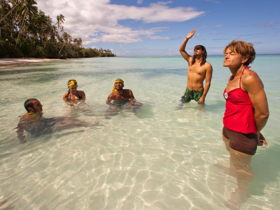 survivor player standing and sitting in the shallow part of the ocean