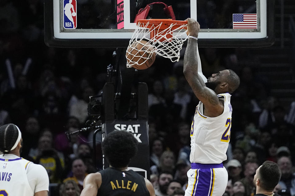 Los Angeles Lakers forward LeBron James dunks in front of Anthony Davis, left, and Cleveland Cavaliers' Jarrett Allen, center, and Max Strus, right, during the second half of an NBA basketball game Saturday, Nov. 25, 2023, in Cleveland. (AP Photo/Sue Ogrocki)