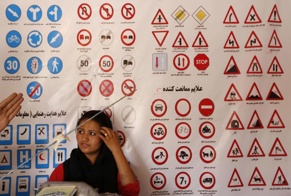 A woman listens to an instructor who explains traffic signs at a driving school in Kabul