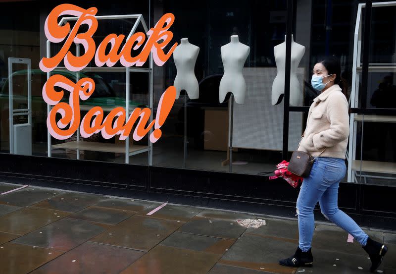 FILE PHOTO: A woman wears a face mask as she walks past a closed retail unit amid the outbreak of the coronavirus disease (COVID-19) in Manchester