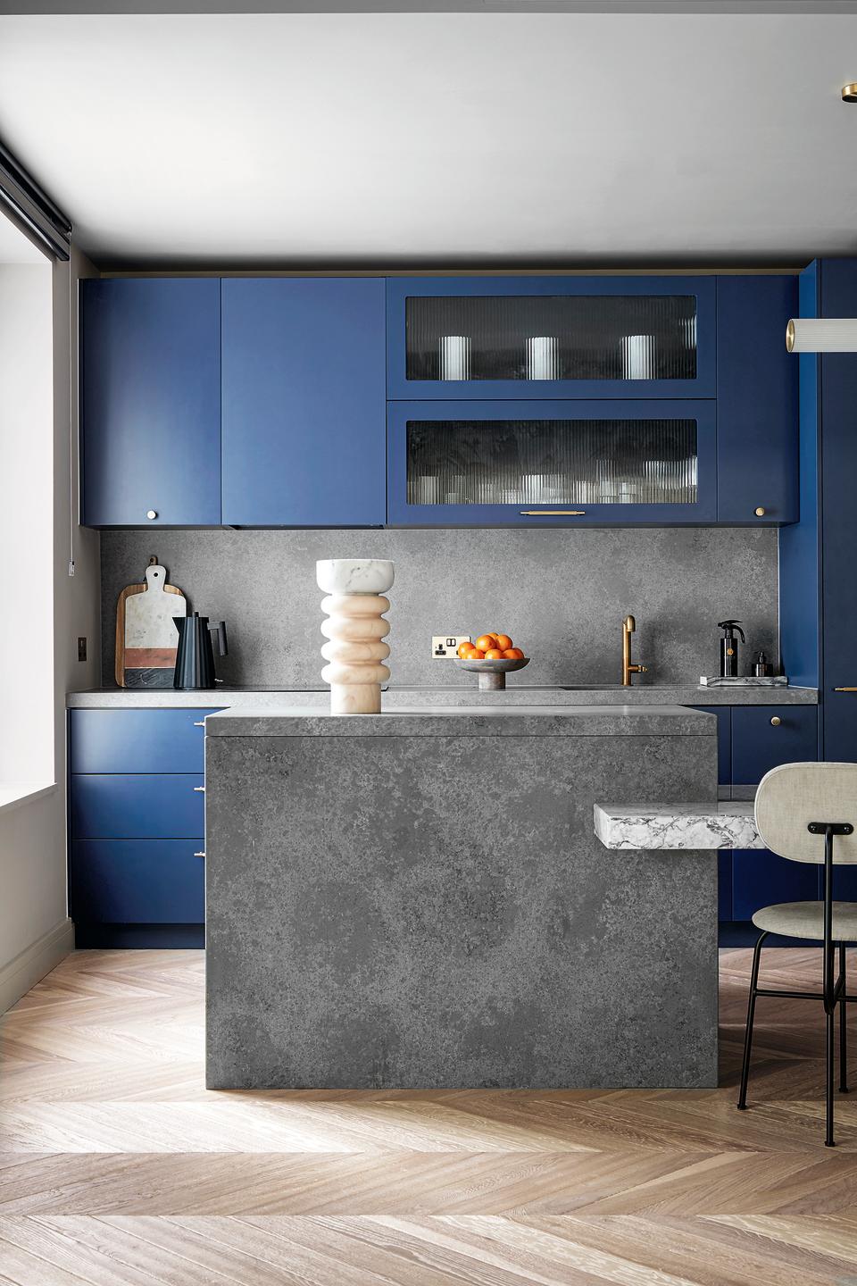 A kitchen with blue cabinetry and a grey stone island