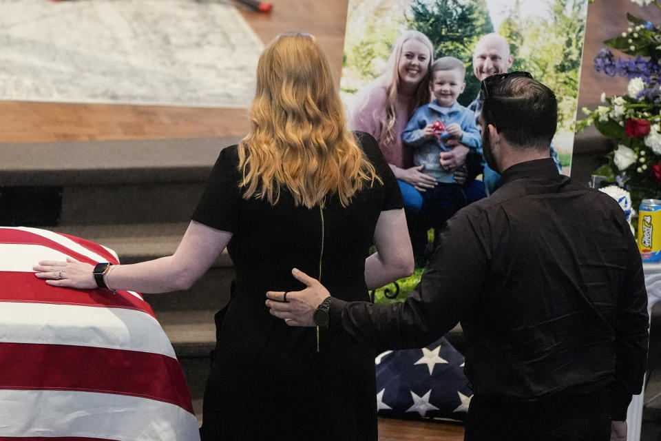 Widow of Officer Joshua Eyer, Ashley Eyer is escorted to the alter by Pastor Justin Wallace during a memorial service for Officer Joshua Eyer, Friday, May 3, 2024, in Charlotte, N.C. Police in North Carolina say a shootout that killed Eyer and wounded and killed other officers began as officers approached a home to serve a felony warrant on Monday. (AP Photo/Chris Carlson)