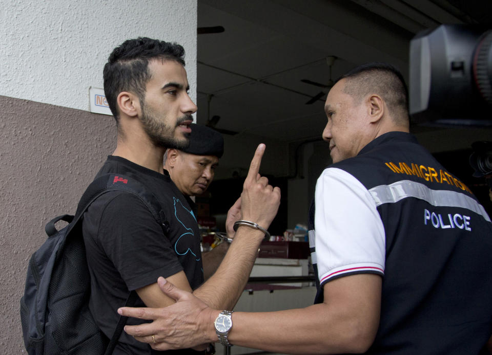 Bahraini football player Hakeem al-Araibi, left, gestures as he is brought in to a court in Bangkok, Thailand, Tuesday, Dec. 11, 2018. A Thai court has ruled that the soccer player who holds refugee status in Australia can be held for 60 days pending the completion of an extradition request by Bahrain, the homeland he fled four years ago on account of alleged political persecution. (AP Photo/Gemunu Amarasinghe)