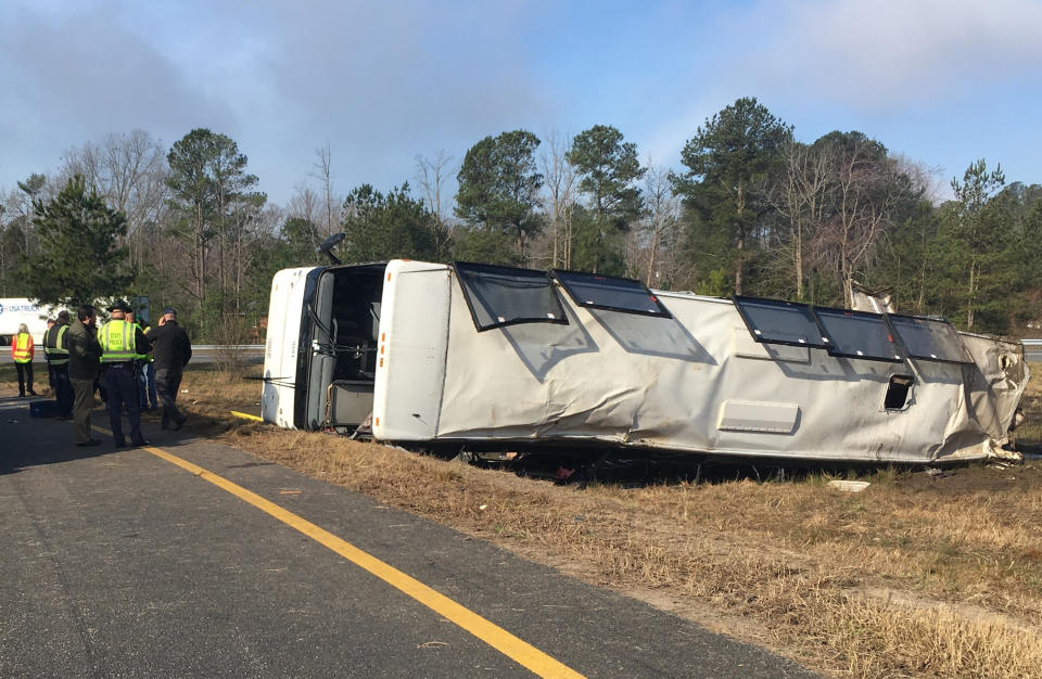 This photo provided by Virginia State Police emergency responders at the scene after a charter bus overturned on an Interstate 95 exit near Kingwood, Va., Tuesday, March 19, 2019. Virginia State Police say in a statement that the Tao's Travel Inc. bus with 57 people aboard overturned on an Interstate 95 exit Tuesday in Prince George County. Police say that as the bus turned onto the exit, it ran off the left side and overturned. (Virginia State Police via AP)