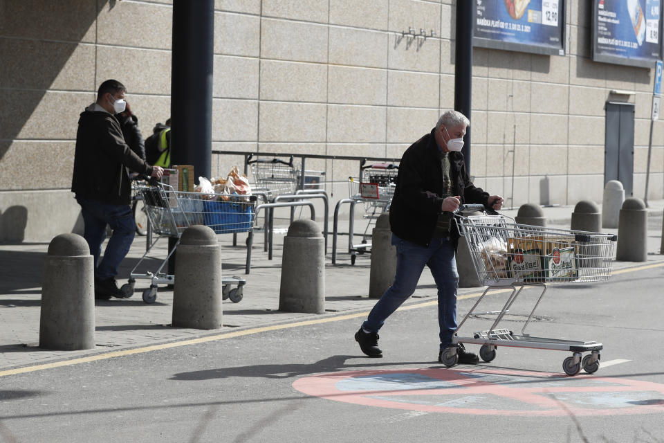 People walk out of a grocery store in Ceska Lipa, Czech Republic, Thursday, March 18, 2021. The upper house of the Czech Parliament, the Senate, rejected legislation that requires supermarkets carry a minimum share of local food, a move to be less dependent on imports. In Thursday's 75-0 vote, the Senators refused to approve the bill to have the share of Czech food in stores that are bigger than 400 sq. meters (4305 sq. feet) at least 55% in 2022 and increase to at least 73% in 2028. (AP Photo/Petr David Josek)