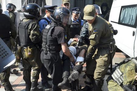 Ukrainian police and national guard officers carry an injured colleague to an ambulance outside the parliament building in Kiev, Ukraine, August 31, 2015. REUTERS/Stringer