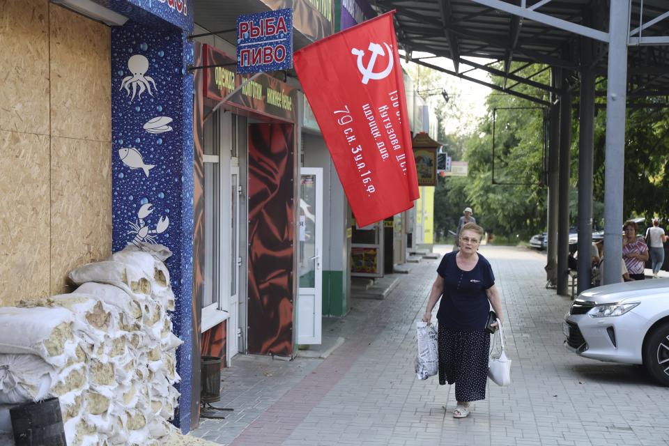 Una mujer pasa junto a una tienda decorada con una réplica de una bandera de la victoria antes de las elecciones locales en Donetsk, la capital de la región homónima ucraniana controlada por Rusia, el jueves 7 de septiembre de 2023, en el este de Ucrania. (AP Foto)