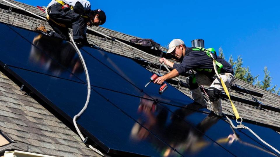 Sun Driven Solar employees Alec Carson, right, and Cesar Acuna, left, install solar panels onto the roof of Bob Kennedy’s Nampa home in November.