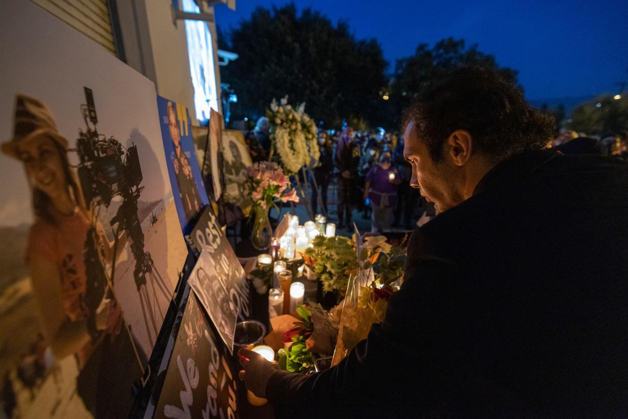 A man pays respects near a photo of cinematographer Halyna Hutchins, who was accidentally killed by a prop gun fired by actor Alec Baldwin, at a memorial table during a candlelight vigil in her memory in Burbank, California on October 24, 2021. - The police investigation into a fatal shooting with a prop gun fired by actor Alec Baldwin on a film set was focusing October 23, 2021 on the specialist in charge of the weapon and the assistant director who handed it to Baldwin. Ukraine-born cinematographer Halyna Hutchins, 42, was struck in the chest and died shortly after the incident Thursday in New Mexico, while director Joel Souza, 48, who was crouching behind her as they lined up a shot, was wounded and hospitalized, then released (Photo by DAVID MCNEW / AFP) (Photo by DAVID MCNEW/AFP via Getty Images)