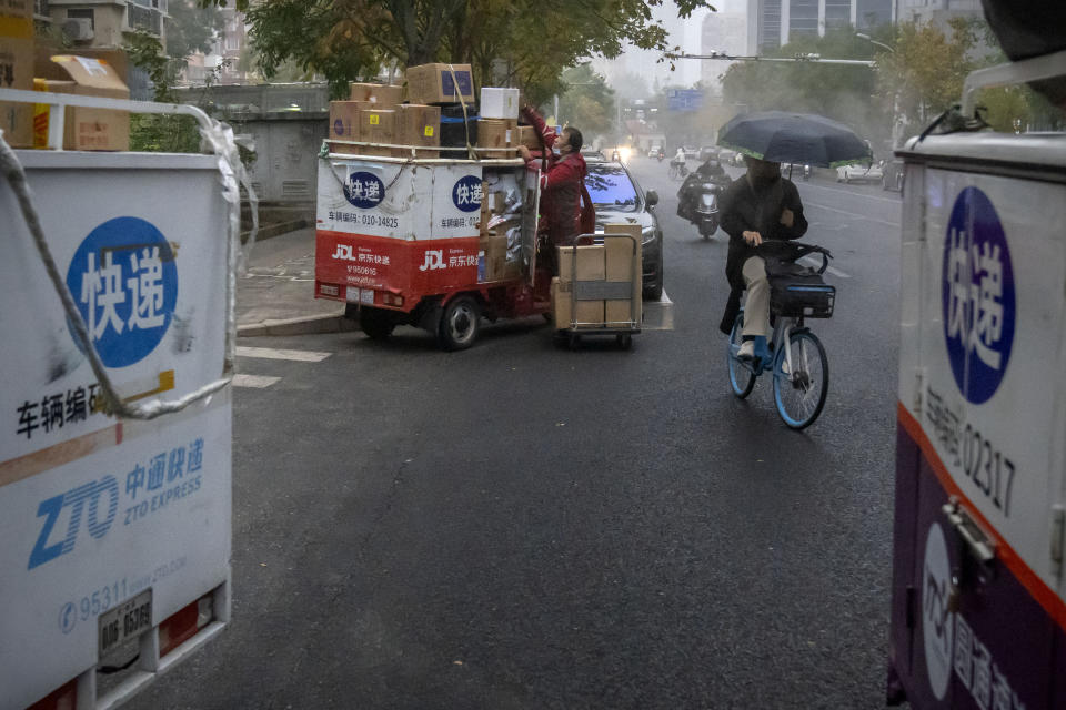 A delivery courier unloads packages near parked carts for other delivery companies along a street in Beijing, Friday, Nov. 11, 2022. China's biggest online shopping festival, Singles' Day, is muted this year with sales numbers expected to grow slowly amid an uncertain economy and COVID-19. Singles’ Day — also known as Double 11 as it falls on Nov. 11 annually — is closely watched as a barometer of consumption in China. (AP Photo/Mark Schiefelbein)