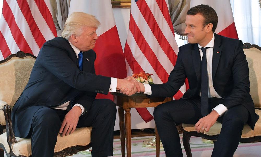 Donald Trump, left, and Emmanuel Macron shake hands in front of French and US flags