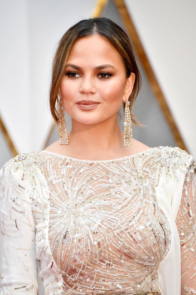 Chrissy Teigen wears Glossier’s Cloud Paint at the Oscars. (Photo: Getty)