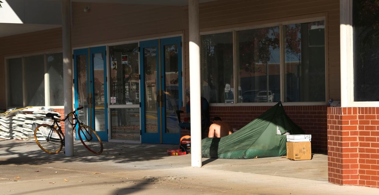 A person sits in a camp site set up on a sidewalk Nov. 6 in downtown Shawnee. The city has recently passed ordinances restricting both the feeding of homeless and sitting or sleeping in downtown Shawnee.