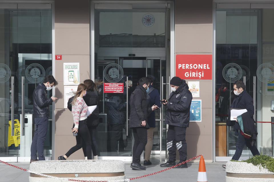 A security official checks people's IDs before the third hearing in the trial of Carlos Ghosn, former Nissan Motor Co. chairman, in Istanbul, Wednesday, Jan. 20, 2021. Turkish prosecutors on Wednesday pushed for maximum 12 years in prison each for a Turkish private airline company official and two pilots who are accused of smuggling Ghosn out of Japan, Turkey's state-run news agency reported.(AP Photo/Mehmet Guzel)