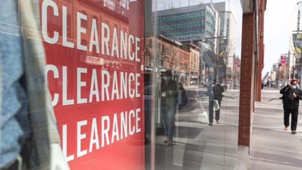 Pedestrians pass a store's window sign advertising a clearance sale on Bank Street in Ottawa in late April 2021. (Brian Morris/CBC - image credit)