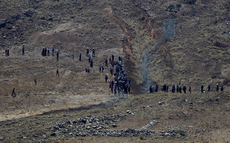 People walk towards the border fence between Israel and Syria from its Syrian side as it is seen from the Israeli-occupied Golan Heights near the Israeli Syrian border July 17, 2018. REUTERS/Ronen Zvulun