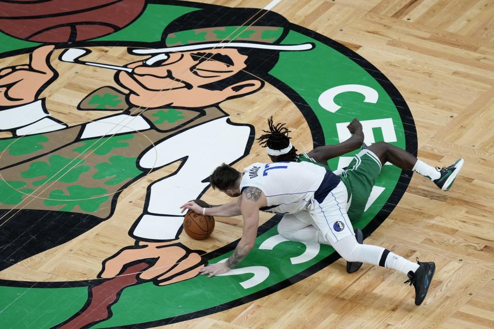 Boston Celtics' Jrue Holiday, right, and Dallas Mavericks' Luka Doncic (77) battle for the ball during the first half of Game 5 of the NBA basketball finals, Monday, June 17, 2024, in Boston. (AP Photo/Michael Dwyer)