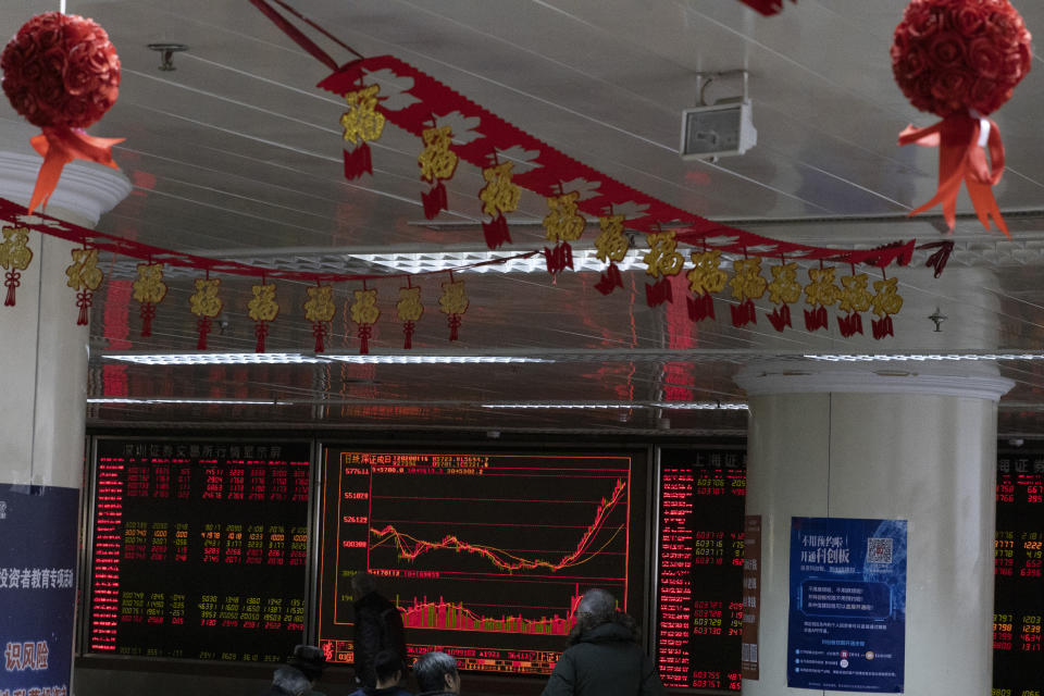 Investors monitor stock prices near Chinese New Year decorations hung up at a brokerage in Beijing Thursday, Jan. 16, 2020. Share prices are mixed in moderate trading in Asia after the U.S. and China signed a preliminary trade agreement that investors hope will bring better relations between the two biggest economies. (AP Photo/Ng Han Guan)