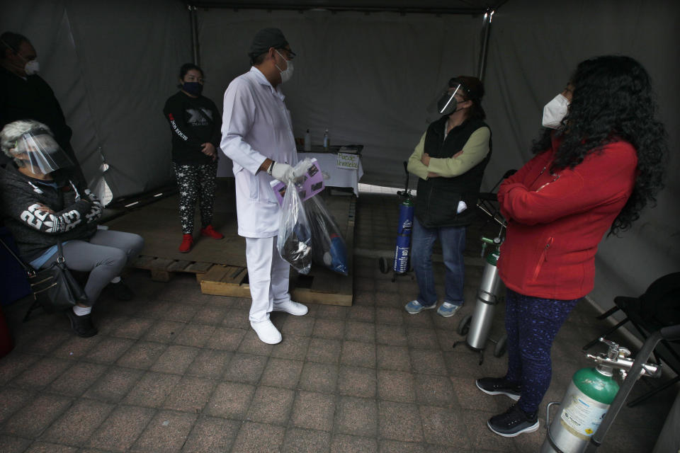 Un trabajador de salud habla con familiares de pacientes con COVID-19 que han sido dados de alta luego de recuperarse de la enfermedad en el Hospital General Ajusco Medio de la Ciudad de México, el miércoles 2 de diciembre de 2020. (AP Foto/Marco Ugarte)