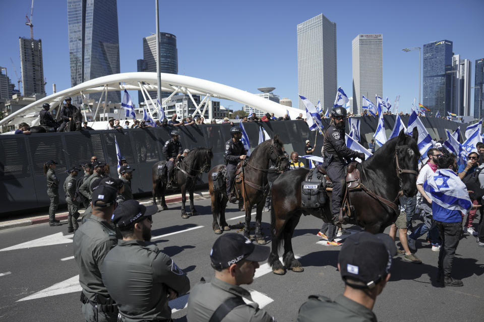 Israeli mounted policemen block protesters against plans by Prime Minister Benjamin Netanyahu's new government to overhaul the judicial system from approaching to the main freeway in Tel Aviv, Israel, Thursday, March 16, 2023. (AP Photo/Oded Balilty)